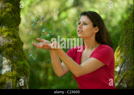 La donna caucasica cercando di catturare le bolle nelle sue mani Foto Stock