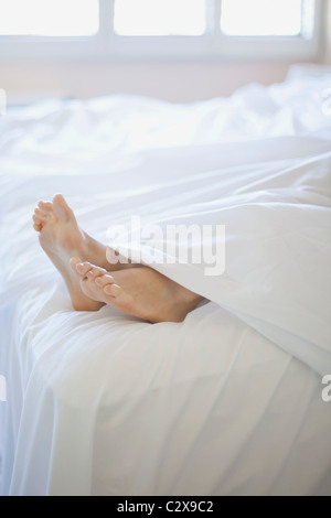 Donna con i piedi sul fondo del letto Foto Stock