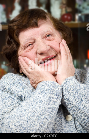 Ritratto di faccia felice di anziani donna senior 80 s a ridere e tenendo le mani sulle sue guance Foto Stock