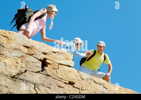 Ritratto di uomo felice aiutando la moglie e il figlio per salire sulla roccia alta Foto Stock