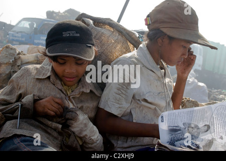 Due bambini operaio ragazze stanno prendendo una pausa dai loro posti di lavoro a un inquinamento discarica di rifiuti in Cambogia. Foto Stock