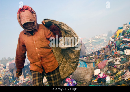 Una donna che vive in condizioni di povertà è la ricerca per la plastica a inquinati e tossici di scarico di rifiuti in Cambogia. Foto Stock