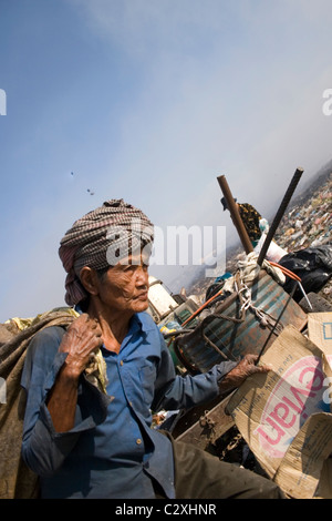 Una donna anziana è la ricerca di materiale riciclabile a inquinata discarica di rifiuti in Cambogia. Foto Stock