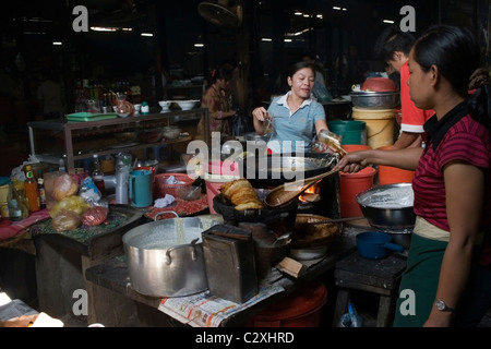 Una donna è la cottura di cibo cambogiano con stufa a legna all'interno del mercato russo in Phnom Penh Cambogia. Foto Stock