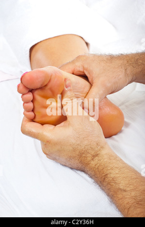 Massaggiatore professionista dando riflessologia plantare per il piede della donna Foto Stock