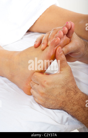 Dettaglio dell'uomo mani facendo massaggio di riflessologia ai piedi di donna Foto Stock