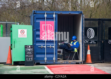 Attendant texting a rifiuti domestici centro di riciclaggio a Prestwich, Bury, Greater Manchester, Inghilterra, Regno Unito Foto Stock