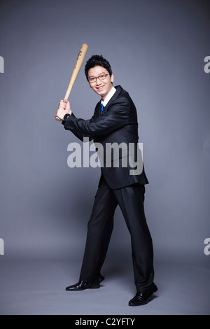 Imprenditore in posa swing baseball bat Foto Stock