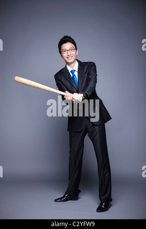 Imprenditore in posa swing baseball bat Foto Stock