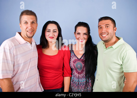 Felice due coppie in piedi in una linea più vicini gli uni agli altri e sorridente su sfondo blu Foto Stock