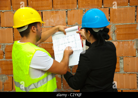 Indietro di due architetti con blueprint lavorando sul sito,l'uomo puntando sul progetto Foto Stock