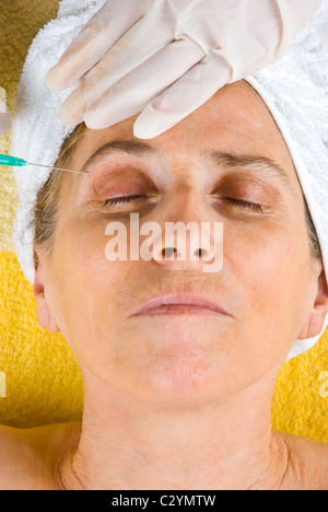 Senior donna essendo iniettato con botox in le sopraciglia Foto Stock