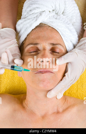 Senior donna riceve una iniezione di Botox nella sua labbra Foto Stock