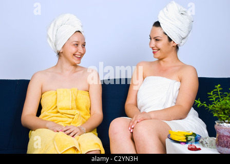 Due donna seduta sul lettino in una spa salone sala attesa e avente una simpatica conversazione e ridere insieme Foto Stock