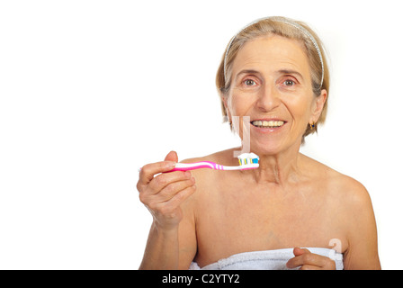 Sorridente donna senior holding spazzolino da denti isolati su sfondo bianco,copia spazio per un messaggio di testo nella parte sinistra dell'immagine Foto Stock