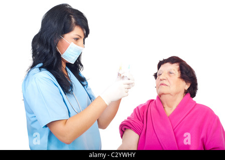 Medico donna tenendo una ampolla di medici con vaccino antinfluenzale e una siringa e la preparazione di iniettare il paziente anziano Foto Stock