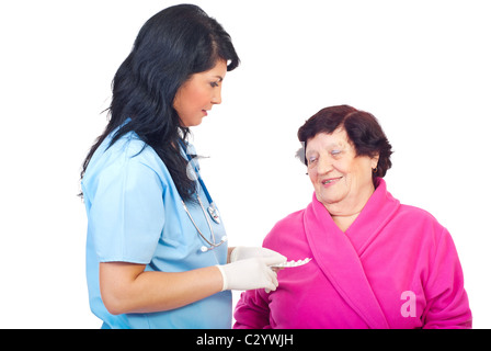 Medico donna dando pillole per una donna anziana e il suo insegnamento come prendere loro isolati su sfondo bianco Foto Stock