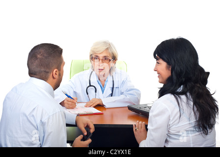 Senior medico donna avente conversazione con coppia giovane in office Foto Stock