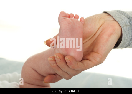 Stretta di mano madre holding neonato piede Foto Stock