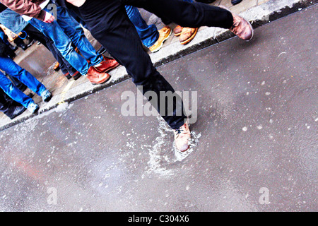 L'uomo passi in una pozza provocati dalla fusione di neve in Oxford Street Londra Foto Stock