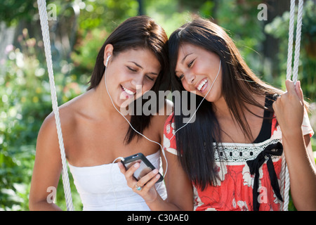 Due ragazze adolescenti la condivisione di un lettore MP3 e sorridente Foto Stock