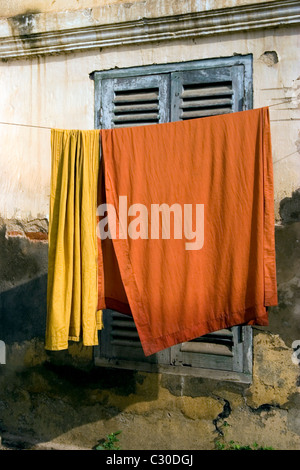 Orange monaco buddista di accappatoi sono appesi su uno stendibiancheria in un tempio fatiscente in Cambogia. Foto Stock