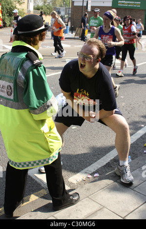 Runner accetta la vaselina da San Giovanni volontario di ambulanza per alleviare il doloroso lo sfregamento sul percorso della maratona di Londra Foto Stock