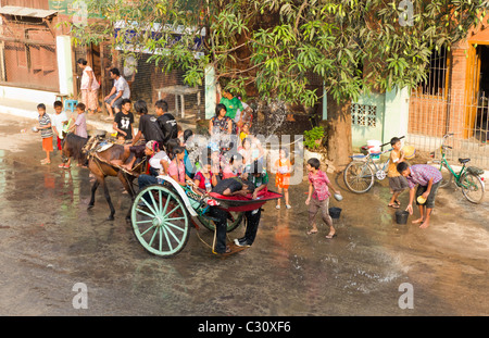 Persone su carrozza Getting irrorato con acqua a Thingyan, il Festival dell'acqua a Mandalay, Myanmar Foto Stock