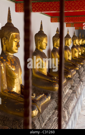 Fila di seduto Golden Buddha attraverso la finestra sbarrata al tempio buddista di Wat Pho a Bangkok, in Thailandia Foto Stock