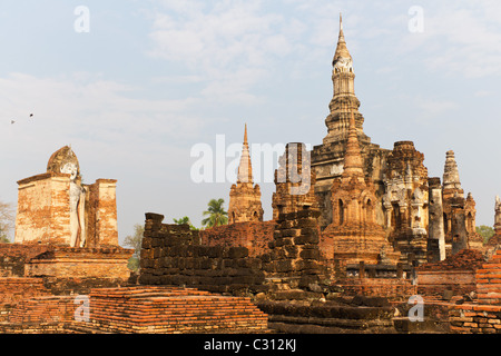 Statua di Budda e i resti di un tempio di Wat Mahathat presso il sito Patrimonio Mondiale dell'UNESCO di Sukothai in Thailandia Foto Stock