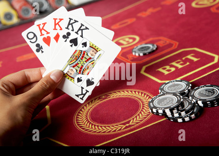 Immagine di cinque carte da gioco in mani con chip nero nelle vicinanze Foto Stock