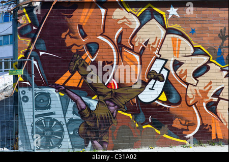 Armonici di graffiti su un lungo muro di mattoni in Munich-Giesing mostrante un tag colorato e i diversi elementi della cultura hip hop, Germania Foto Stock
