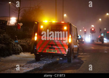 AA van parcheggiato a lato della strada in una notte d'inverno con un po' di neve sul marciapiede Foto Stock