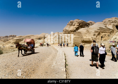 I turisti a piedi verso il basso il lungo percorso inclinato che conduce al Rose Red città di Petra. Giordania, mentre un cavallo e carrello vai in altro modo Foto Stock