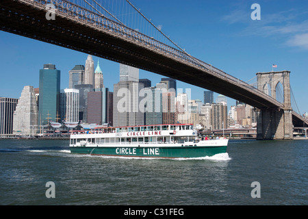 Un cerchio di barca di linea che passa sotto il ponte di Brooklyn, East River, Manhattan, NEW YORK CITY, STATI UNITI D'AMERICA, STATI UNITI D'AMERICA Foto Stock