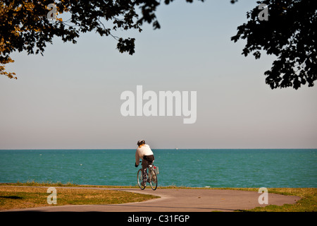 Un ciclista viaggia lungo il lago Michigan nel centro cittadino di Chicago, IL. Foto Stock