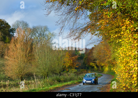 Piccola berlina guidato lungo il vicolo del paese in autunno, il Costwolds, REGNO UNITO Foto Stock