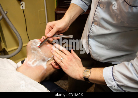 Un uomo riceve una barba da un rasoio in un negozio di barbiere in Omaha, Nebraska, STATI UNITI D'AMERICA Foto Stock