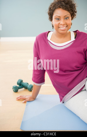 Donna africana seduto sul materassino yoga con manubri Foto Stock