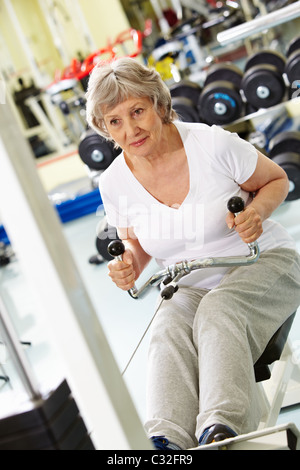 Foto di donna attiva i muscoli di pompaggio su attrezzatura speciale Foto Stock