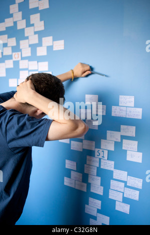 Ragazzo adolescente di revisione per la matematica un livello con schede di revisione bloccata sulla sua parete di camera da letto. Foto Stock