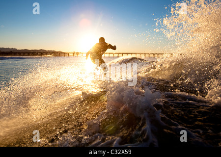 Un surfista imposta per un'aria mentre cavalcate un'onda a Port Hueneme spiaggia nella città di Port Hueneme, la California il 22 dicembre 20 Foto Stock