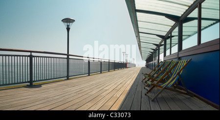 Svuotare sdraio allineate su un molo sul lungomare Foto Stock