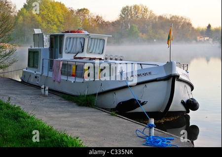 Canal chiatta ormeggiata al mattino presto sul fiume Yonne, Francia, a Charmoy. La nebbia in aumento dopo il fiume Foto Stock