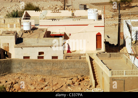 Oman, Qalhat, vista di detriti che giace nella parte anteriore delle tradizionali case in stile, veduta distante di una persona che cammina Foto Stock