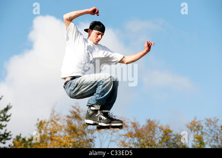 Giovane ragazzo adolescente uomo jumping con pattini pattini a rotelle in linea su U ramp a concorrenza all'aperto Foto Stock