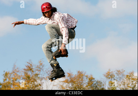 Giovane ragazzo adolescente uomo jumping con pattini pattini a rotelle in linea su U ramp a concorrenza all'aperto Foto Stock