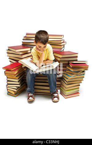 Foto del giovane ragazzo a leggere un libro mentre è seduto sui libri Foto Stock