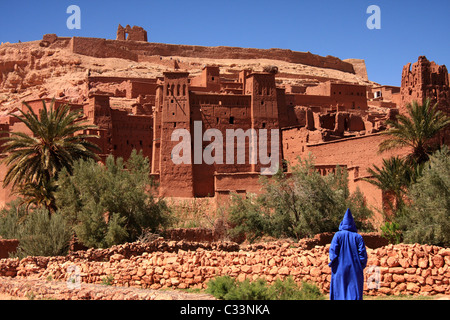 Persona che indossa Marocchino tradizionale jellabah, pause di Ait Benhaddou villaggio fortificato, Atlas, regione del sud del Marocco Foto Stock