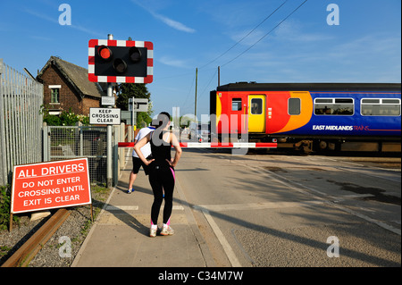 Per chi ama fare jogging in attesa presso un passaggio a livello mentre un locale dei pendolari treno passa Beeston nottingham England Regno Unito Foto Stock